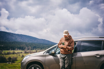 Man travel by car and using smartphone in mountains on vacation trip, making browsing phone and gps.