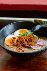 ramen bowls with noodles, pork, chicken, boiled egg and vegatables served with seaweed salad