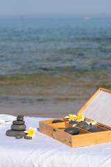 Massage hot with tropical flower on massage table on the beach near the sea prepared by professional masseur for relax in tropical massage spa procedures.