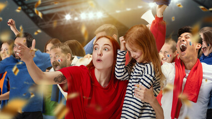 Young woman, sport fan showing little girl her favourite football team. People, football fans attending match to watch game and cheer up team. Sport, leisure time, emotions, hobby and entertainment
