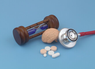 Brain aging and mental health care concept. Human brain with stethoscope, drugs and hourglass.