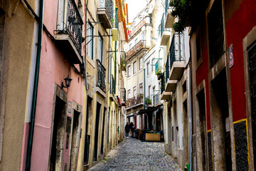 Fototapeta na wymiar Two young women walk up a narrow street in Lisbon