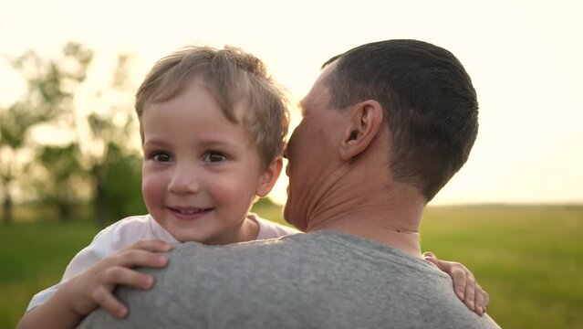 son hugging dad in the park. happy family a father day kid dream concept. baby baby boy walking with dad in nature in his arms. lifestyle baby hugging dad in the park