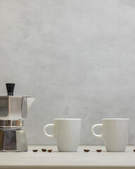 Metal geyser coffee maker on table with cup
