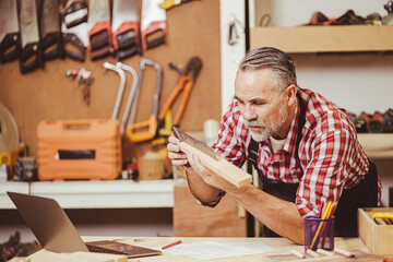 Senior professional male caucasian diy wood working making home furniture in workshop, home renovate.