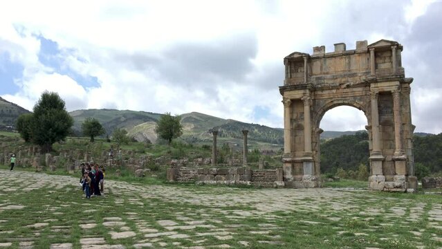 Tourists and kids standing near the Arch of Caracalla in the ancient Roman city of Cuicul. Djemila, Setif, Algeria