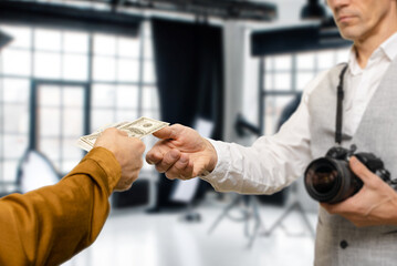 Male photographer with professional photo equipment taking payment for his work, successful...