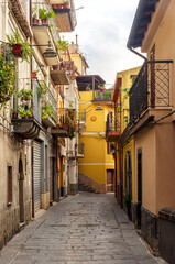 Fototapeta na wymiar beautiful narrow medeterranean street with vintage buildings , beautiful windows and picturesque balcony with attributes of traditional italian country life