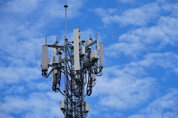 Telecommunication tower of 4G and 5G cellular. Macro Base Station. 5G radio network telecommunication equipment with radio modules and smart antennas mounted on a metal against cloulds sky background.