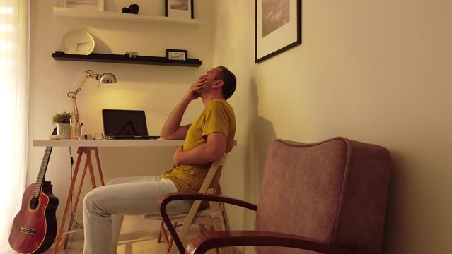 Man with stomach pain and headache while working at home on a laptop.