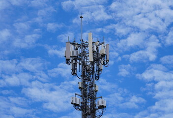 Telecommunication tower of 4G and 5G cellular. Macro Base Station. 5G radio network telecommunication equipment with radio modules and smart antennas mounted on a metal against cloulds sky background.