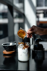 Close-up of woman's hand holding iced coffee in cafe