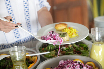 
Woman taking food from a buffet line