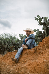 Cowboy under the vast sky, surrounded by cacti, working on a farm