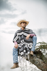 Cowboy wearing a poncho sitting under a tree in the sky