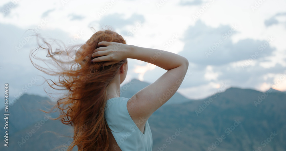 Wall mural carefree girl with red hair raising her hands up to the wind, embracing freedom and tranquility, enj