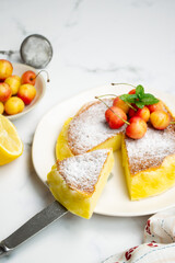 Japanese cotton cheesecake with cherries and powder sugar on top. White marble background