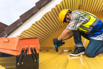 Roofer man using screwdriver installing metal shhet on roof, Engineer Home improvment