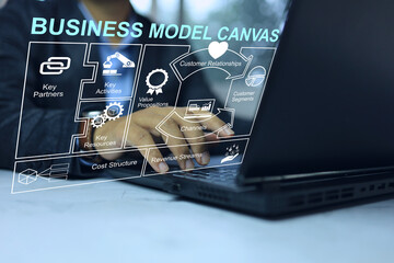 Businessman planning business a plan with business model canvas through a laptop on the desktop for...