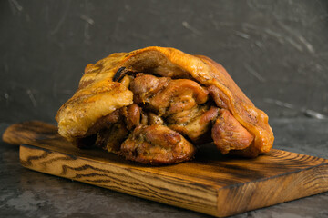 Pork knuckle baked in the oven with chicken. Various baked meats on a wooden cutting board on a dark background, rustic style.