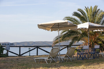 Retro style sun chairs and parasol in the tropical garden with a seaview