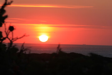 at the sea the red-golden sun shines out from behind the clouds before it sets