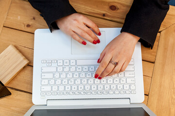 Female hands with red manicure on the background of a white laptop