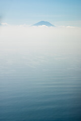 Fototapeta premium bird's eye view of the Agung volcano, minimalistic landscape, only the silhouette of the mountain, clouds and ocean.
