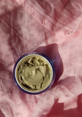 jar with cream on pink linen fabric