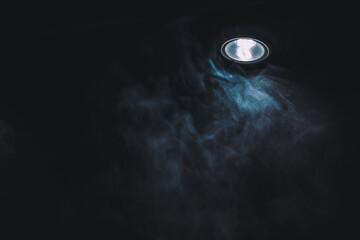 studio light with smoke. smoky room lit by a blue lamp. lamp illuminating smoke. interior wall covered in smoke