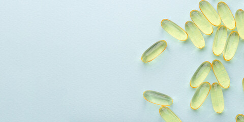 Omega 3 fish liver oil capsules on blue background. Top view, flat lay, copy space.