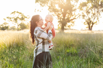 Young australian country woman with baby outside in warm sunlight on farm