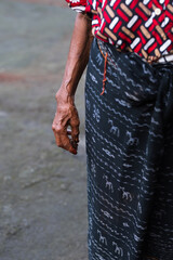 Close-Up of an Elderly Woman's Hand in Traditional Indonesian Clothing.