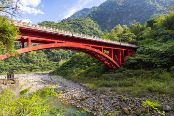 Shakadang bridge over the Liwu River at the entrance of the Shakadang Trail, one of many stunning hiking trails in the Taroko National Park Taiwan. The red steel bridge cross the crystal clear stream
