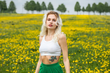 Naklejka na ściany i meble Young beautiful blonde woman posing in a spring field of dandelions