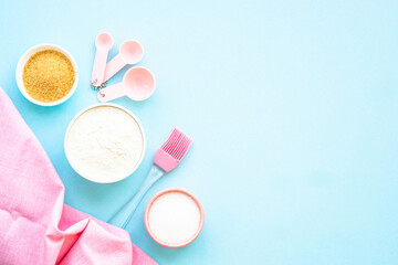 Food baking background on blue. Ingredients for cooking, flour, sugar, eggs. Flat lay.