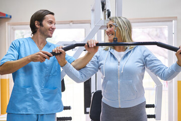 Male physiotherapist training senior woman at rehab center