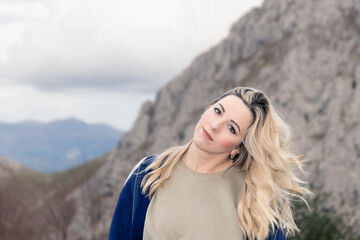 Blonde Beauty Amidst the Mountains: A Captivating Gaze Towards the Camera