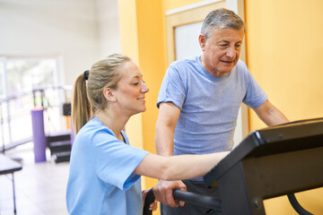 Young physiotherapist assisting senior man on treadmill