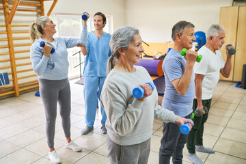 Male therapists assisting elderly people exercising at rehab center