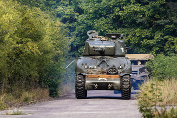 Fototapeta premium An American World War II Sherman drives on the road between the trees.