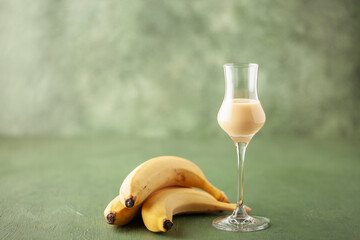 Banana liqueur in grappas glasses and fresh  bananas on the table. Copy space