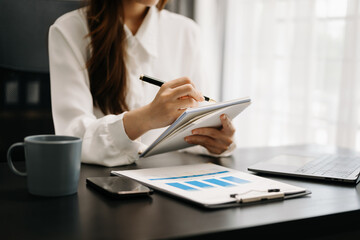 Business woman sitting front tablet ,laptop computer with financial graphs and statistics on monitor.at office.