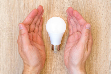 Hands covering led light bulb