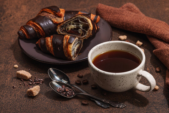 Cup of coffee and chocolate croissants in dark tones. Morning good mood, French breakfast concept