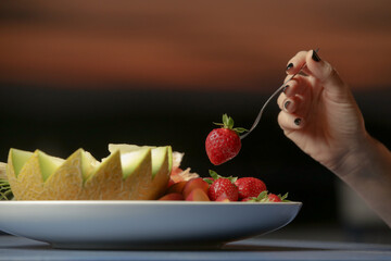 Woman taking strowberry from a fruit platter
