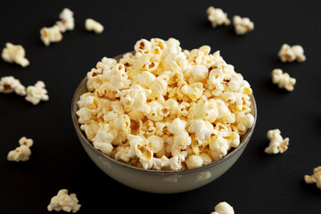 Homemade Buttered Popcorn with Salt in a Bowl on a black background, side view.