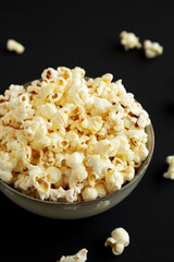 Homemade Buttered Popcorn with Salt in a Bowl on a black background, low angle view.