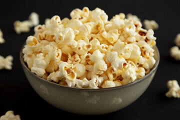 Homemade Buttered Popcorn with Salt in a Bowl on a black background, low angle view. Close-up.