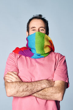 vertical portrait of madure man covering his face with a rainbow scarf. lgbt concept